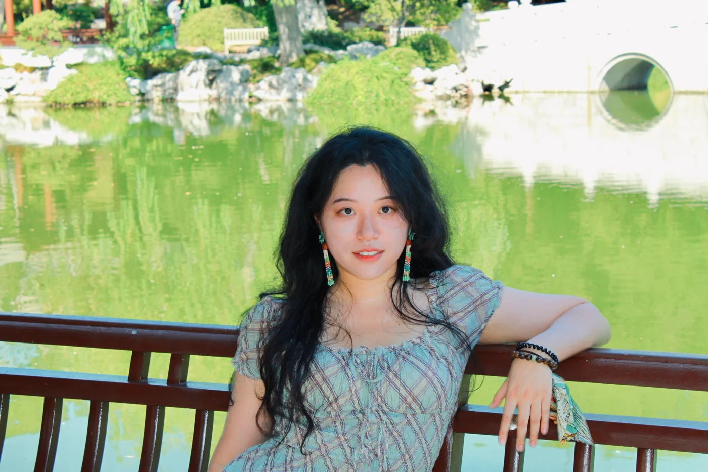 Tina Jiang seated beside a garden pond